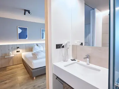 a bathroom with a sink and a bed in a room at Hotel Balga Natur- und Bikehotel in Balgach