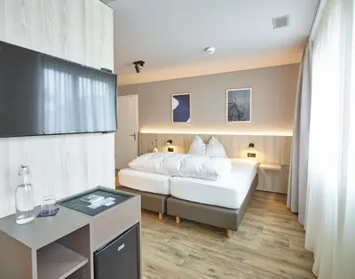 a bedroom with a white bed and a desk and a room at Hotel Balga Natur- und Bikehotel in Balgach