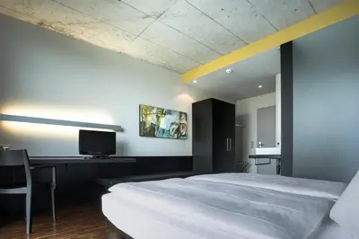 a bedroom with a bed and a desk and a tv at Hotel Kreuzlingen am Hafen in Kreuzlingen