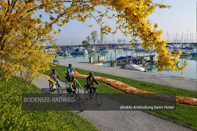 three people riding bikes on a path near a marina at Hotel Kreuzlingen am Hafen in Kreuzlingen