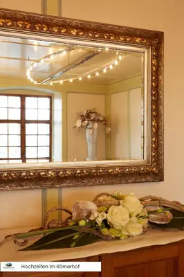 a mirror above a table with a bouquet of flowers at Hotel de Charme Römerhof in Arbon