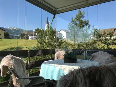 three sheep sitting at a table in front of a window at Sonnastuba in Wildhaus