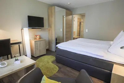 a bedroom with a bed and a desk with a computer at Herisau Swiss Quality Hotel in Herisau