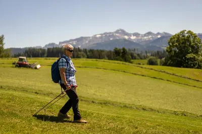 a man walking in a field with a backpack and a golf club at Herisau Swiss Quality Hotel in Herisau