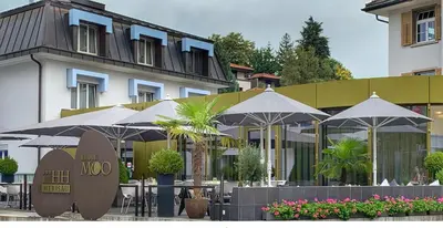 a restaurant with tables and umbrellas in front of a building at Herisau Swiss Quality Hotel in Herisau