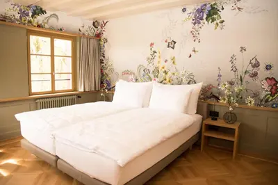 a bedroom with a large bed with flowers on the wall at Hotel Restaurant Falkenburg in St. Gallen