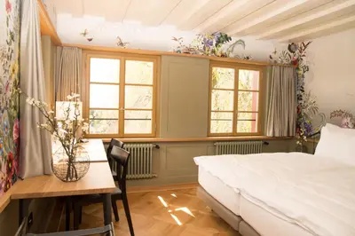 a bedroom with a bed and a table and windows at Hotel Restaurant Falkenburg in St. Gallen