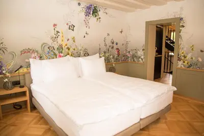 a bedroom with a large white bed with flowers on the walls at Hotel Restaurant Falkenburg in St. Gallen