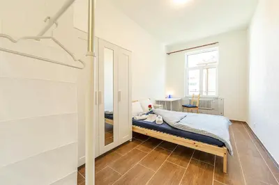 a bedroom with a bed with blue sheets and a desk at YELLOW INN - SIMPLE ROOMS -- OLMA Messen & Autobahn 1 Min, HSG 6 Min, Spital 7min, günstige Parkplätze in St. Gallen