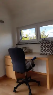 a desk with a chair in front of two windows at Attika Ferienwohnung Merk in Kreuzlingen
