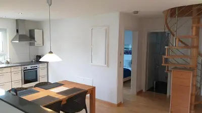 a kitchen and dining room with a table and a staircase at Attika Ferienwohnung Merk in Kreuzlingen