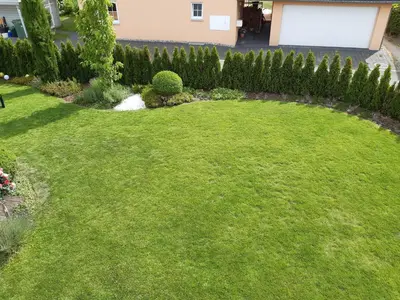 a garden with a circular lawn with a hedge at Attika Ferienwohnung Merk in Kreuzlingen