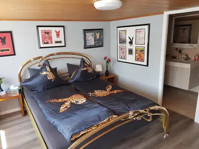 a bed with a blue comforter and some pictures at Gasthaus Sternen in Degersheim