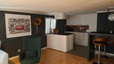 a kitchen with white cabinets and a green chair at London Apartments in Rheineck