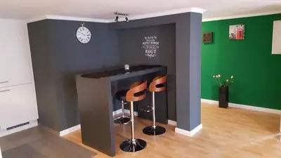 a room with two stools in front of a wall with a clock at London Apartments in Rheineck