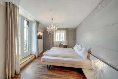 a bedroom with a large bed and a chandelier at Schloss Wartensee in Rorschacherberg