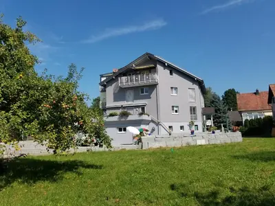 a large white house on a hill with a yard at Studio direkt am Bodensee in Thal