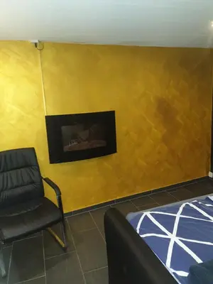 a room with a chair and a yellow wall at Grosses Apartement 2 Schlafzimmer am Bodensee in Arbon