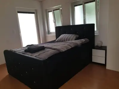 a black bed in a room with windows at 3 Doppel Zimmer Apartement in 9320 Arbon in Arbon