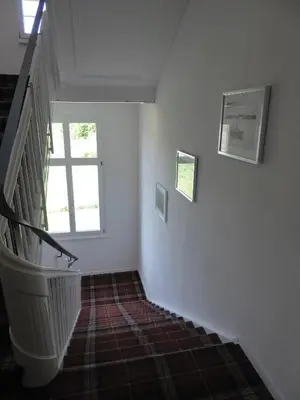 a hallway with a staircase with two windows and a stair case at VILLA TAEGERMOOS in Tägerwilen