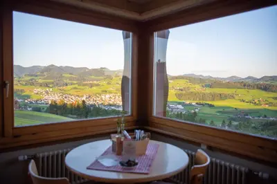 a table in a room with two large windows at Restaurant und Kaeserei Berghof in Ganterschwil