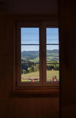 a window with a view of a field through it at Restaurant und Kaeserei Berghof in Ganterschwil