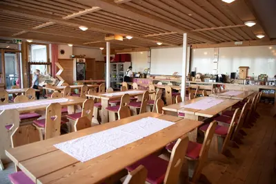 an empty restaurant with wooden tables and chairs at Restaurant und Kaeserei Berghof in Ganterschwil