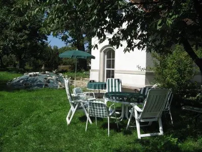 a group of chairs and a table with an umbrella at 2-Zimmer-Ferienhäuschen am Bodensee in Güttingen
