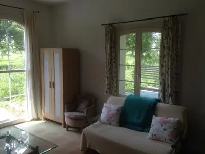 a living room with a glass table and a large window at 2-Zimmer-Ferienhäuschen am Bodensee in Güttingen