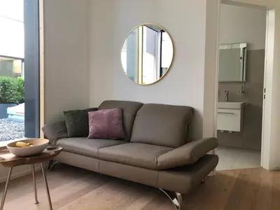 a living room with a couch and a mirror at Hotel Profis in Diepoldsau