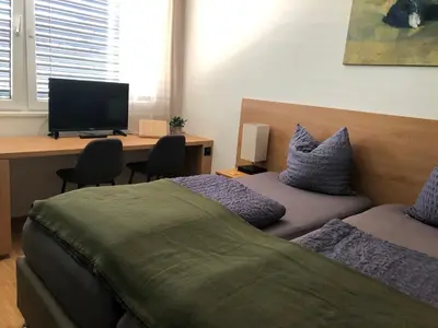 a bedroom with a bed and a desk with a computer at Hotel Profis in Diepoldsau