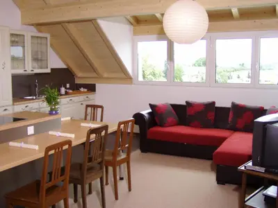 a living room with a red couch and a table at Gästehaus am Sonnenfeld in Sommeri