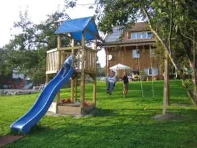 a playground with a blue slide in a yard at Gästehaus am Sonnenfeld in Sommeri