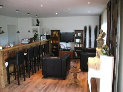 a living room with a bar with black chairs at Gästehaus am Sonnenfeld in Sommeri