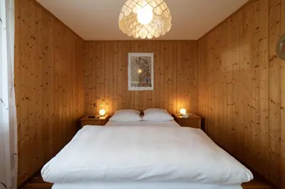 a bedroom with a large white bed with two lamps at Sonnhalde in Wildhaus
