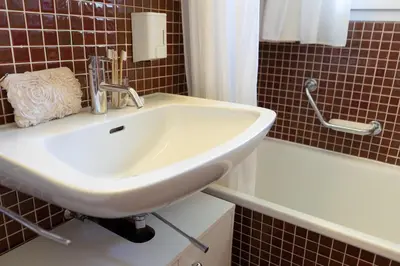 a white sink in a bathroom next to a bath tub at Frühweid in Unterwasser