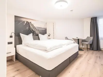 a bedroom with a large white bed and a desk at Traube Restaurant & Hotel in Appenzell
