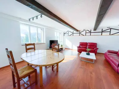 a living room with a table and a red couch at Säntisecho - in der Natur zu Hause in Urnäsch