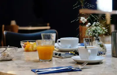 a table with a glass of orange juice and coffee at Hotel Eastside (free parking garage) in St. Gallen