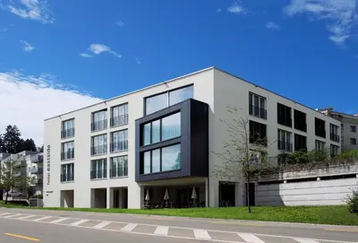a white building with black windows on a street at Hotel Eastside (free parking garage) in St. Gallen
