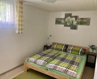 a bedroom with a bed and a table with a lamp at Ferienwohnung Haus am Bach in Toggenburg in Wildhaus