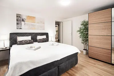 a bedroom with a large bed with white sheets at VISIMO Apartments Felsenstrasse St Gallen - Elegant heritage building in a quiet neighbourhood in St. Gallen