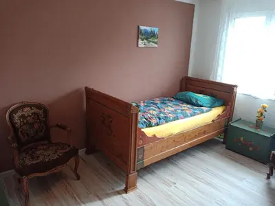 a bedroom with a bed and a chair and a window at B&B Im Bitzi in Zuzwil