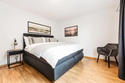 a bedroom with a large bed and a chair at SOHO 11 !Gratis Parken, Free Parking! in Kreuzlingen