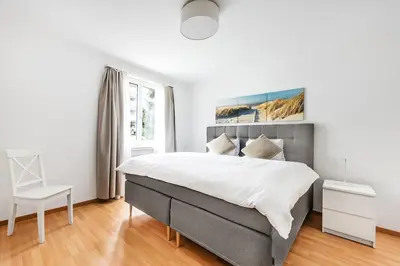 a white bedroom with a large bed and a chair at SOHO G !Gratis Parken, Free Parking! in Kreuzlingen
