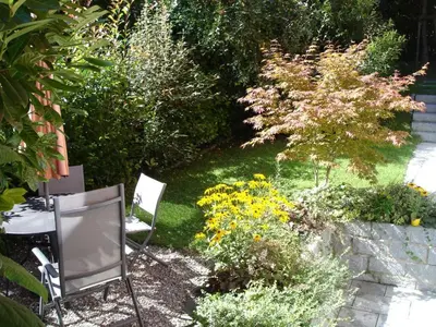 a garden with two chairs and a table and flowers at Ferienwohnung am Bach in Kreuzlingen