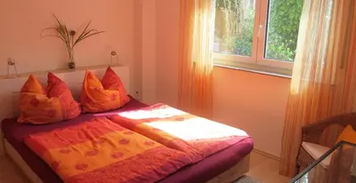 a bedroom with a bed with orange sheets and a window at Ferienwohnung am Bach in Kreuzlingen
