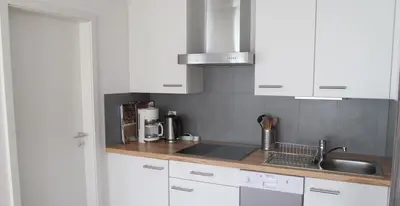 a kitchen with white cabinets and a sink at Ferienwohnung am Bach in Kreuzlingen