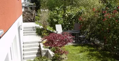 a garden with a table and chairs and flowers at Ferienwohnung am Bach in Kreuzlingen
