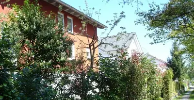 a red house with trees in front of it at Ferienwohnung am Bach in Kreuzlingen